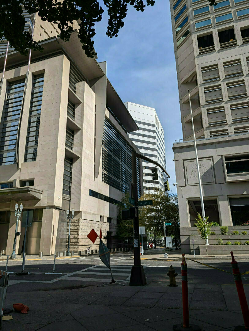Auto-generated description: A cityscape featuring modern office buildings under a clear sky, surrounded by street signs and construction cones.