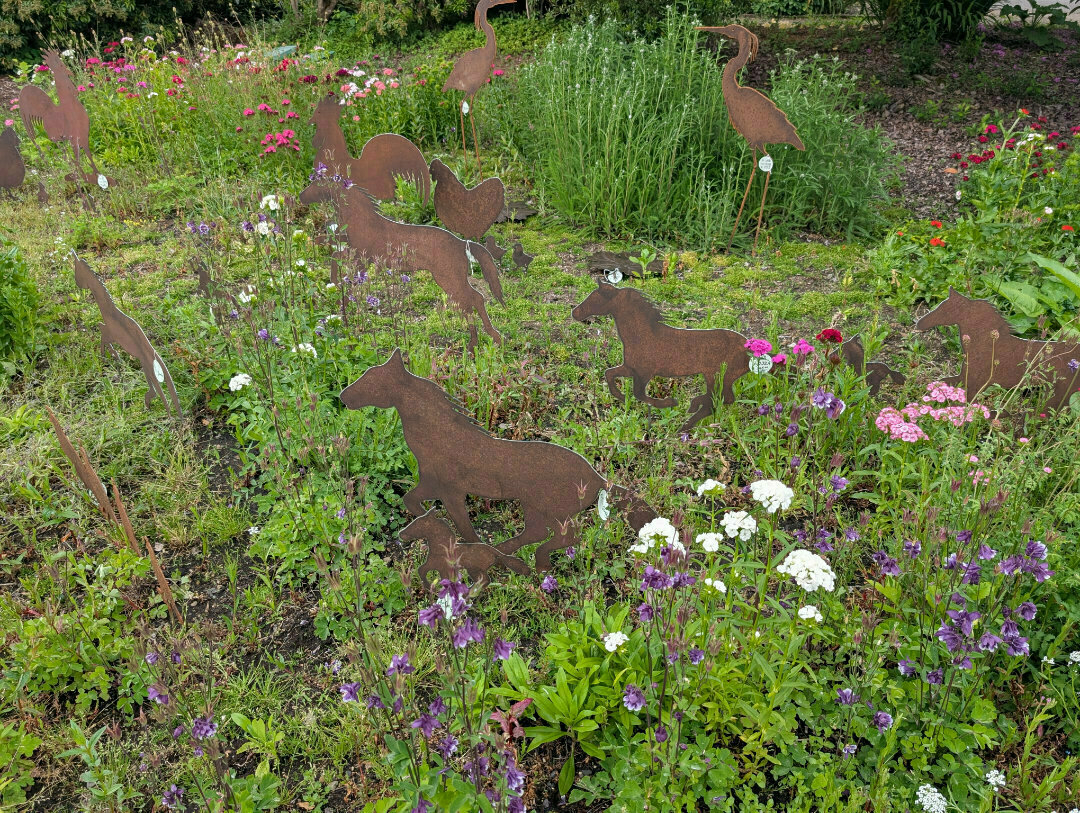 Auto-generated description: A garden features metal animal silhouettes amongst vibrant wildflowers.