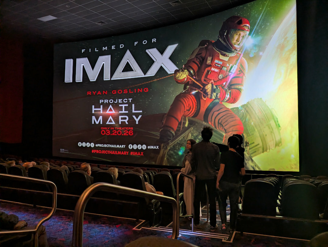 Photo of an IMAX screen inside a movie theater highlighting the movie Project Hail Mary.